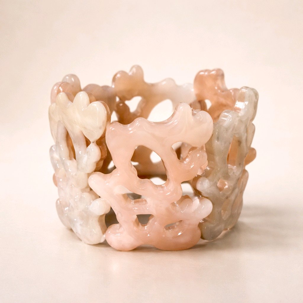 Brazalete de resina acrílica con diseño orgánico calado en tonos beige y rosa empolvado marmoleado sobre fondo neutro