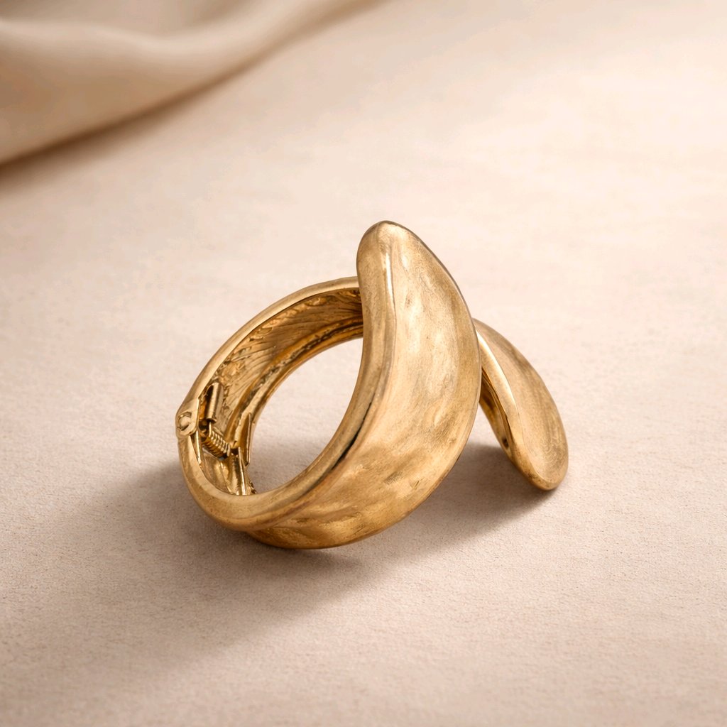 Mujer luciendo brazalete dorado de diseño organico y escultórico de la marca Muzetto, estilo lujo silencioso.