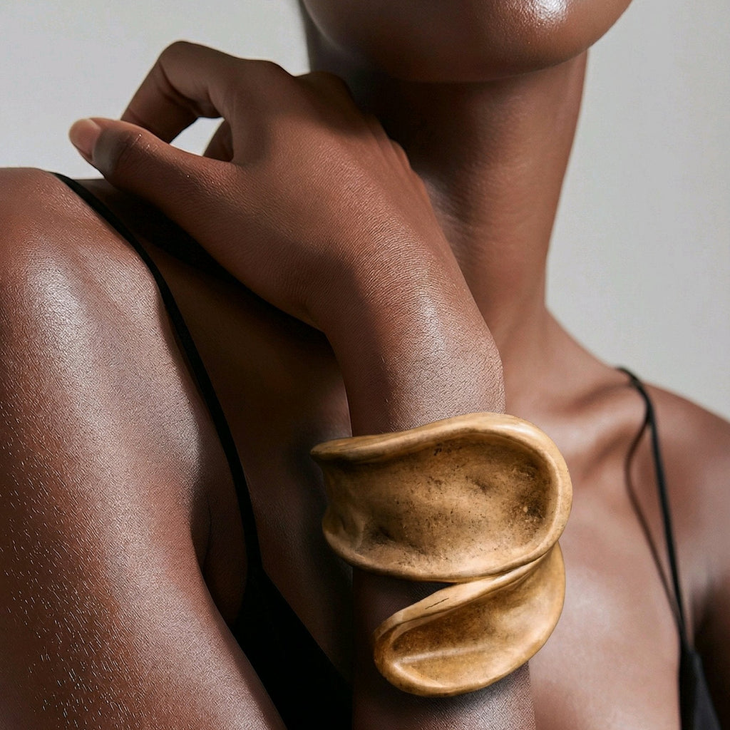 Mujer luciendo brazalete dorado de diseño organico y escultórico de la marca Muzetto, estilo lujo silencioso.