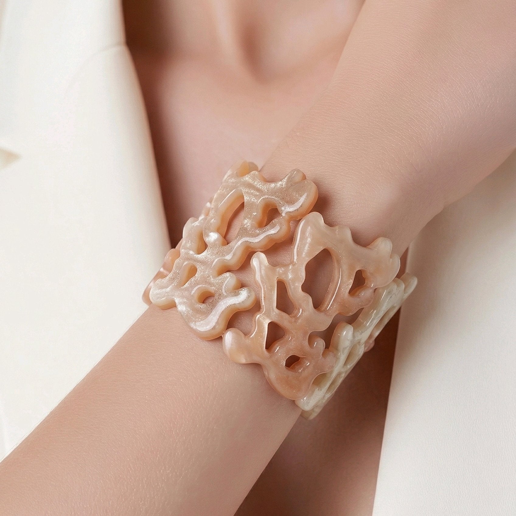 Mujer con blazer blanca luciendo brazalete de resina calado efecto nácar de la colección Riviera de Muzetto.