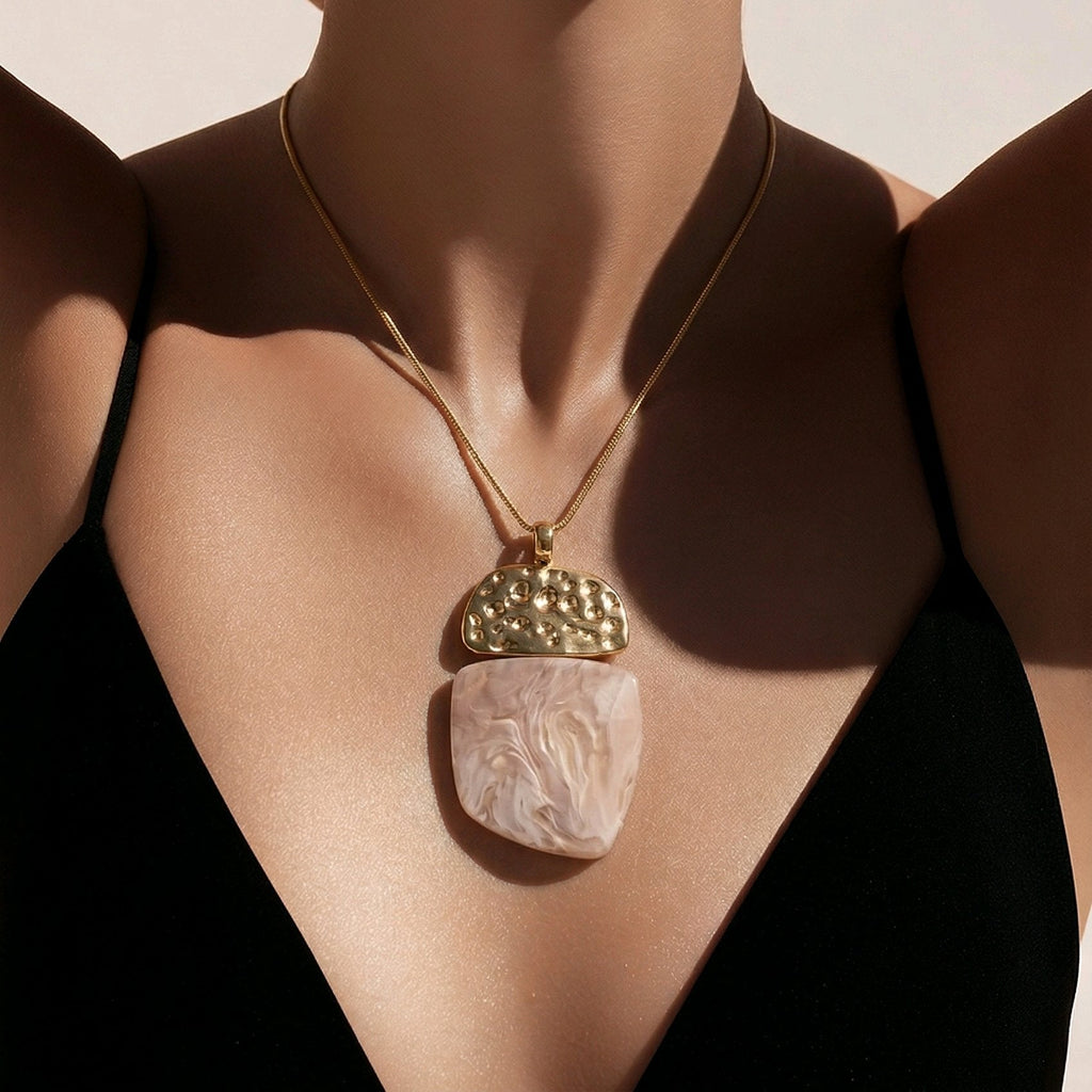 Primer plano de mujer con el collar Máxima rosa arena, colgante de resina y metal dorado sobre cordón de seda.