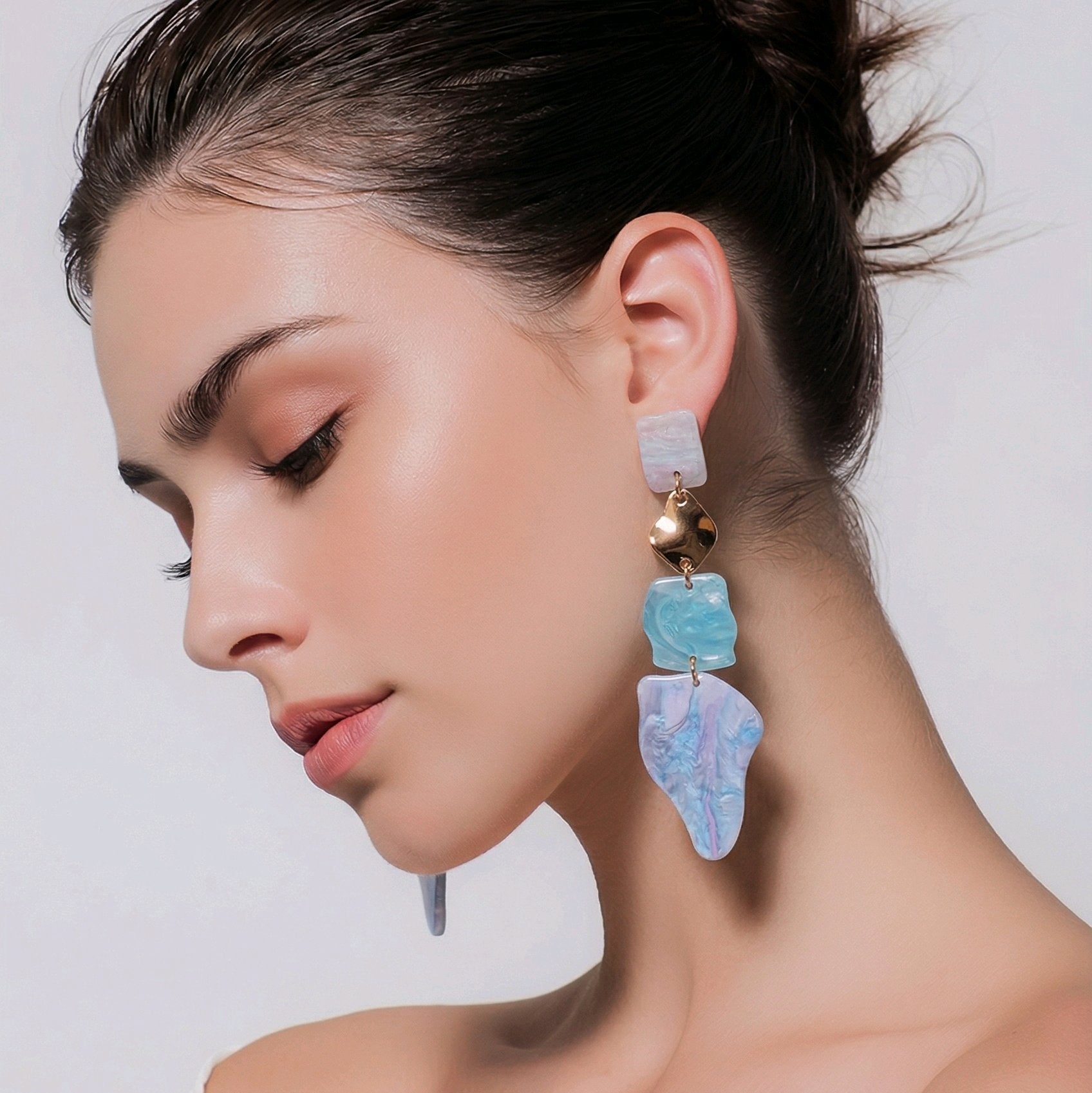 Pendientes colgantes asimétricos en acrílico azul océano y oro, bisutería de diseño escultórico ligera y sin níquel colección Riviera.
