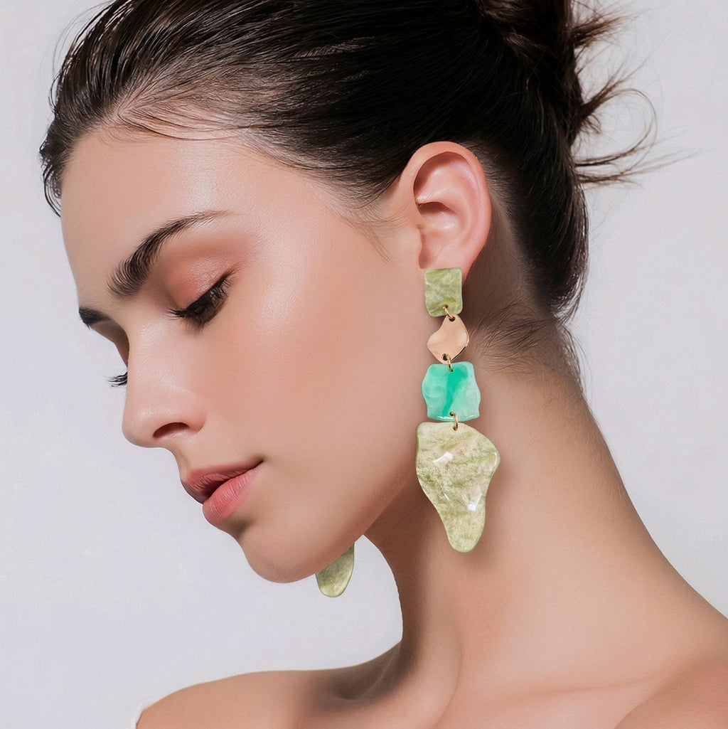 Pendientes largos de diseño orgánico con piezas de resina marmoleada en verde jade y metal dorado, estilo vanguardista Muzetto.
