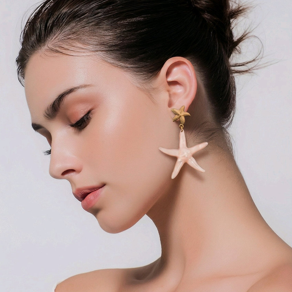 Pendientes colgantes con forma de estrella de mar en color rosa empolvado y metal dorado, diseño ligero y sin níquel de Muzetto.
