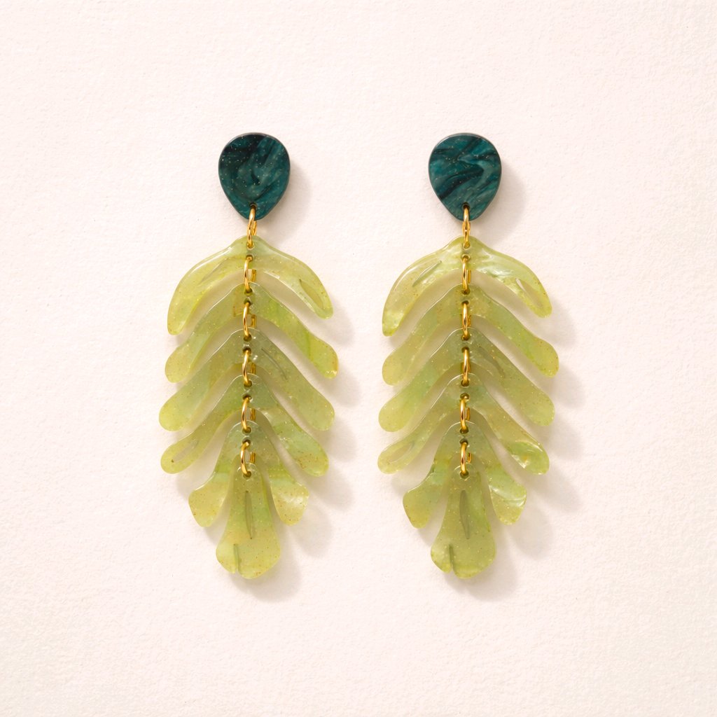 Pendientes largos articulados con forma de hoja de palma en resina verde marmoleada y eslabones dorados, estilo botánico Muzetto.