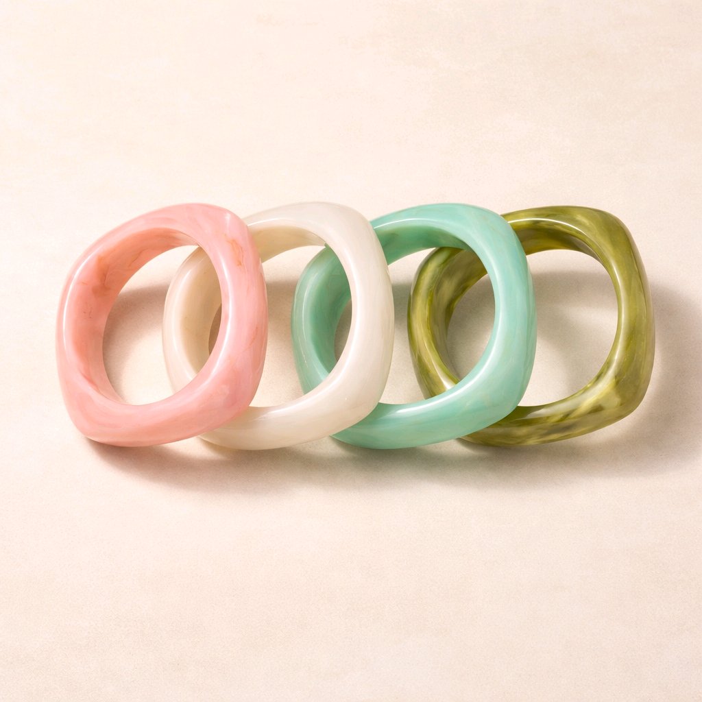 Pulseras de resina marmoleada Muzetto con diseño orgánico de curvas suaves y ángulos sutiles en colores rosa empolvado, marfil, verde agua y oliva sobre fondo neutro